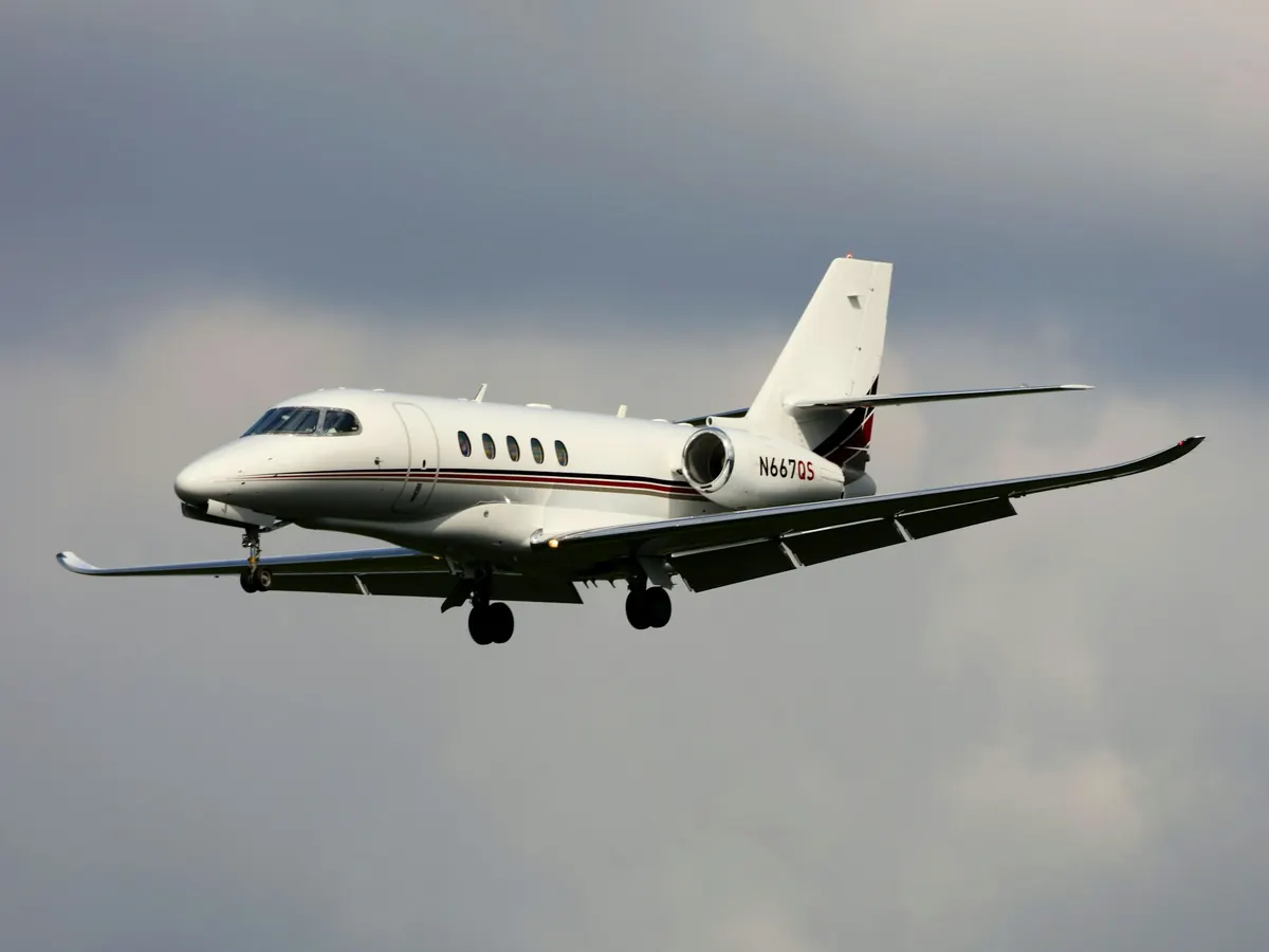 Light business jet climbing through grey cloud