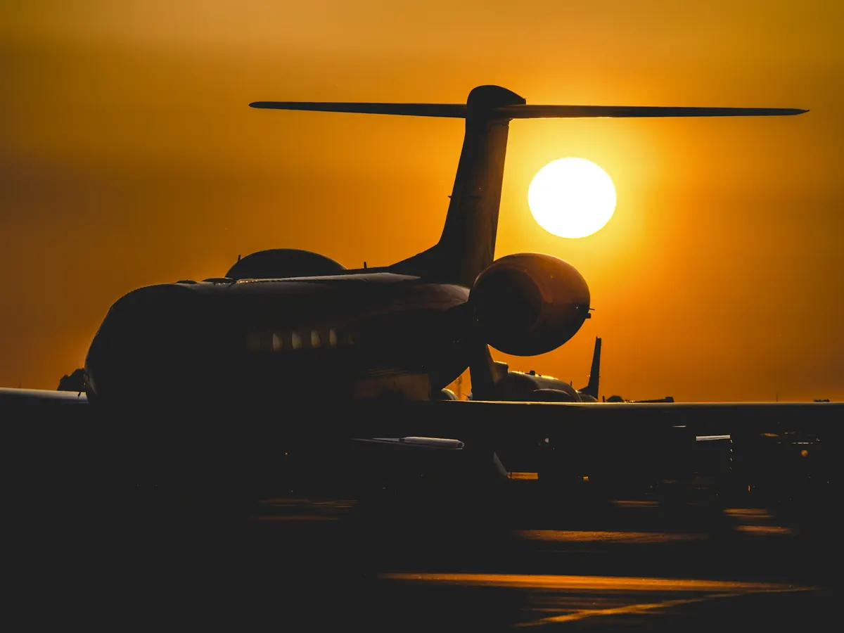 Long-range business jet in silhouette against a low sun